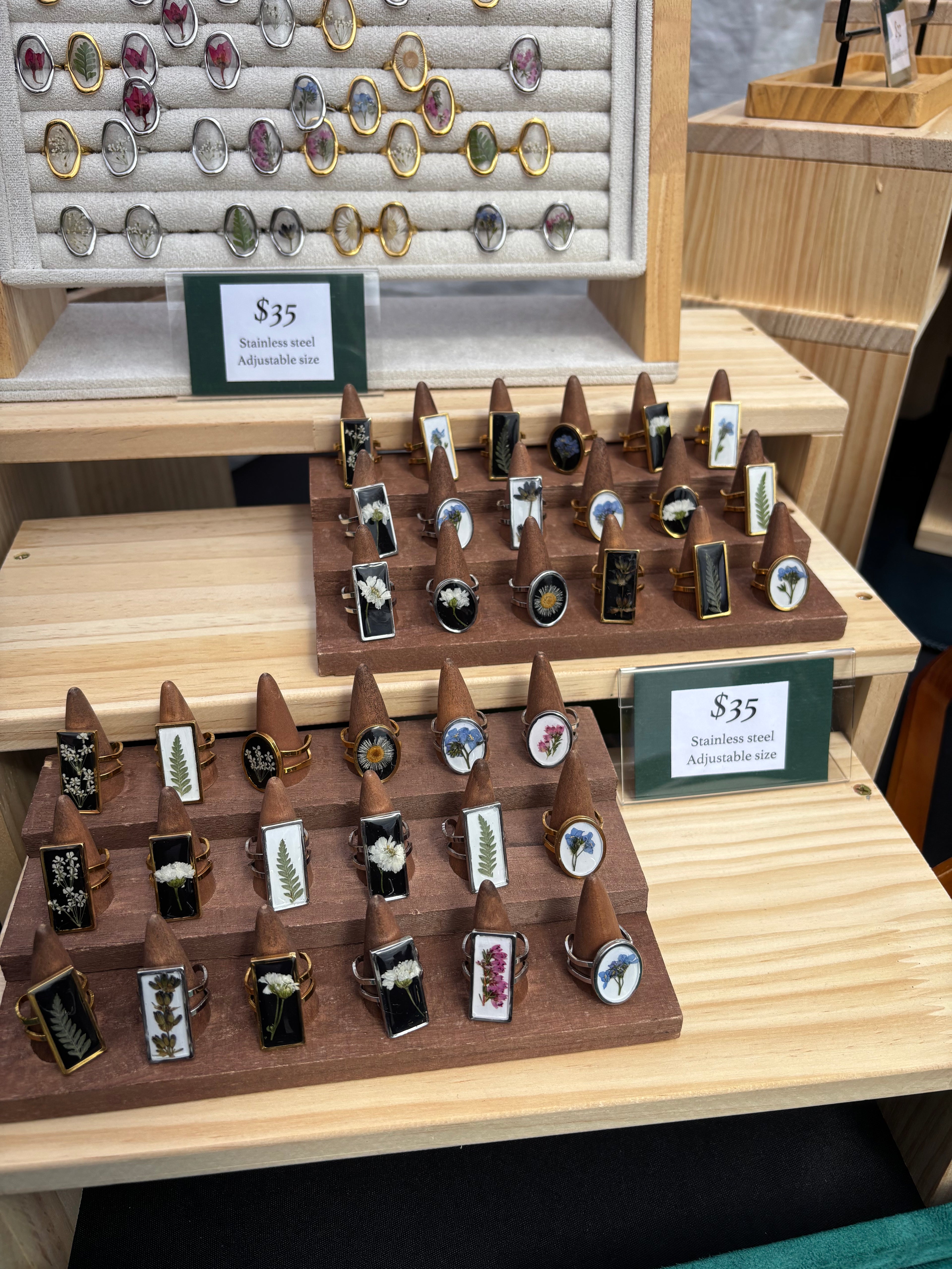 Collection of floral rings on a wooden stand with price tags.